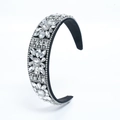 Close-up of black velvet headband featuring sparkling crystal and diamond flower detailing - Silver