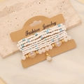 Detailed macro of layered bohemian beaded bracelets with blue and white crystals on card - White