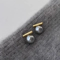 Minimalistische Goldstab- und graue Perlenohrstecker auf grauem Strickhintergrund - Gold Grau Glasperle