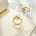 Close-up of golden pear-cut zircon ring with wavy band on a book casting a heart shadow - Gold - Cut-out Teardrop Zircon
