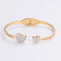 Detalle de una pulsera de corazón dorada con cristales brillantes sobre un fondo blanco - Dorado