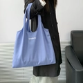 Blue canvas tote bag with Simplicity print shown on model for capacity and style - Light Blue