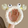 Close-up of a plush white crab-shaped headband with big eyes and green pincers - Headband-Cream White Crab