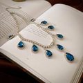 Macro view of crystal flower necklace with blue teardrop pendants on an open vintage book - 37# Necklace - Silver - Teardrop