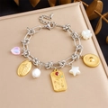Detailed shot of gold bracelet with sun, pearl, and colorful heart charms on a tray - Rose Pearl Star Style (B1712)