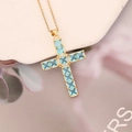 Detailed close-up of a gold cross necklace with a light blue zircon stone inlay - Lake Blue