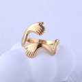 Vue détaillée d'une bague mains qui s'enlacent en acier doré sur un décor blanc - Doré / Ouvert Réglable