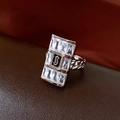 Makro-Detail des rechteckigen Rings mit silbernem S-Logo auf schwarzem Emaille und Kettendesign - Silber