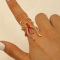 Gros plan d'une bague araignée gothique dorée avec cristaux rouges au doigt - Style Forme d'Araignée / Or KC Strass Rouge (WG-0483)