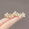 Elegant gold hair clip with five white pearl flowers and rhinestones held on fingers - Flower Design
