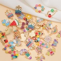Colorful enamel alloy owl and animal pendants displayed on a soft white fabric background - Mixed Glitter Styles