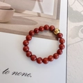 Detail of red agate bead elastic ring with a single polished gold bead on magazine background - Elastic Free Size / Red Stone
