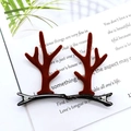 Cute brown reindeer antler hair clips with bells on a vintage book background - Coffee Antler