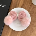 Gros plan d'une barrette à cheveux en tricot rose avec pompons sur une assiette blanche - Rose