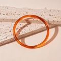 Detalle de una pulsera de acrílico ámbar con textura de mármol sobre superficies pétreas - Brazalete-Café