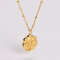 Primer plano del colgante dorado con relieve floral en una cadena fina de estilo francés - Dorado