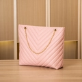 Pink V-quilted faux leather bucket bag with elegant gold chain strap on wooden surface - Pink