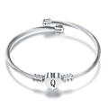 Detail of silver cable bangle featuring a heart charm with black letter Q engraving - Letter Q / Steel