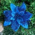 Close-up of blue glittered artificial poinsettia flower on a Christmas tree branch - Blue