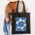 Black canvas tote bag with Greek Evil Eye floral print worn by a model in casual style - Design K-Floral Eye-Black