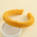 Detailed shot of yellow plush headband resting on white ceramic cup with soft texture - Yellow