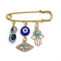 Gold safety pin brooch with blue evil eye beads and Fatima hand charms on white backdrop - Pin with Hollow Hamsa and Rhinestone Eye