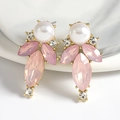 Close-up of teardrop earrings with pink crystals and pearls on a marble plate - Pink