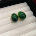 Detailed close-up of emerald green oval gemstones set in vintage gold earrings on a display box - Emerald Cabochon Style (16#)