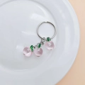 Macro view of clear pink peach resin pendants with green leaves on silver keychain - Peach (No Buckle)
