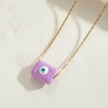 Macro shot of purple rectangular Evil Eye pendant with golden chain on white background - Purple