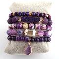 Detail of five-piece purple bohemian beaded bracelets with natural stone pendants on cushion - Purple