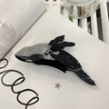 Detailed view of a whale-shaped hair claw clip in grey acetate on an open book - Black Grey Whale