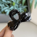 Close-up of black glossy bow-shaped hair claw clip held in hand for size comparison - Glossy Black - Small Bowknot