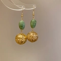 Makroansicht chinesischer Harzohrringe mit hohlen Goldblumenkugeln und grünen Perlen - Ohrringhaken / Gold