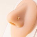 Macro detail of a gold letter T nose stud with clear zircon stones on a silicone model - Letter T / Gold