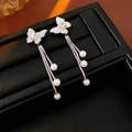 Dettaglio di orecchini a farfalla con nappe d'argento e perle bianche su pelle nera - Stile Farfalla e Perla Argento (Perno Argento-Placcato Vero)