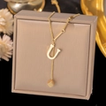Close-up of golden necklace with letter U pendant and cube charm on a jewelry box - Letter U-Gold