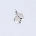 Macro detail of silver baby feet charm with heart cutout and mirror polished finish - Steel