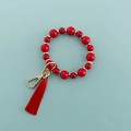 Détail d'un porte-clés bracelet en perles rouges avec accents dorés et pompon rouge - Rouge