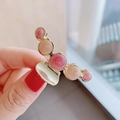 Detail of gold metal hair claw clip with pink and beige swirl pattern pearl accents - Purple-Pink Marble