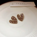 Detailed close-up of brown enamel heart earrings with white polka dots in a ceramic tray - Coffee Polka Dot