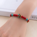 Bracelet bohème tissé main avec perles rouges et turquoise au poignet du mannequin - Rouge et Bleu Mélangés