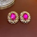 Dettaglio macro di orecchini vintage dorati con gemma rosso rosa e cristalli - 22# Perno d'argento - Ovale con Motivo Dorato