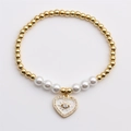 Dettaglio del bracciale con perle dorate e ciondolo a cuore con malocchio - Bianco