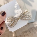 Detail of bow-shaped hair clip with pearls and rhinestones on a gold metal base - Bow