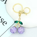 Detailed view of cherry keychain with purple rhinestones and golden metal ring hardware - Purple Rhinestone Cherry