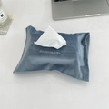 Close-up of blue velvet tissue box cover with gold 'Happiness' embroidery on white desk - Gray Blue