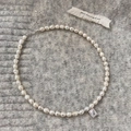 Dettaglio macro di collana di perle barocche con ciondolo in zircone su tessuto in maglia - Perla Irregolare / Collana di Perle con Zirconia Quadrata Argentata
