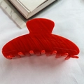Translucent red acetate claw clip for hair styling on a soft white textile background - Red Stripe Acetate