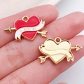 Arrow heart jewelry pendant in red enamel with gold plating shown on hand palm - Red Arrow Through Heart (21200)